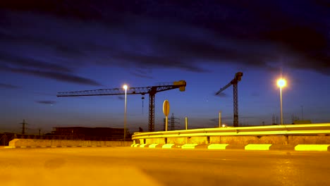 Cars-passing-fast-forward,-through-an-industrial-zone-with-cranes-in-the-background-and-at-dusk