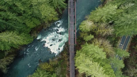 Slow-overflight-above-railroad-tracks-crosses-river-and-through-trees