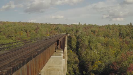 Flying-beside-a-rusty-railroad-trestle-during-an-early-fall-golden-hour-AERIAL