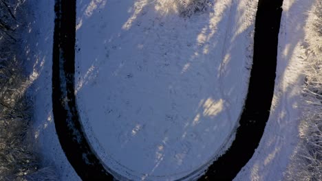 Luftaufnahme-Im-Winter-Von-Einer-Engen,-Kurvenreichen-Straße-Bis-Zu-Einer-Verschneiten-Landschaft-Unter-Blauem-Himmel-–-Wunderschöner-Pulverschneetag