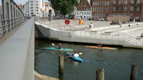 Static-shot-from-bridge-showing-people-paddling-kayak-during-sunny-day-in-Lübeck-old-town