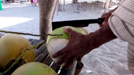 Man-Chopping-A-Coconut-On-The-Beach