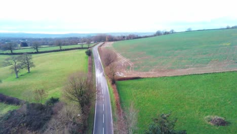 Aerial-view-over-main-road-by-a-house-and-farmland