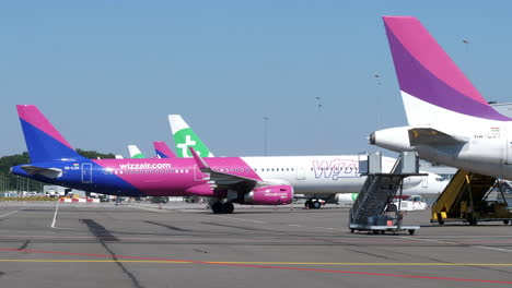 Ein-Pushback-Schlepper-Schiebt-Ein-Flugzeug-Der-Fluggesellschaft-Wizzair-Auf-Dem-Vorfeld-Des-Flughafens-Eindhoven-In-Eindhoven,-Niederlande-–-Totale