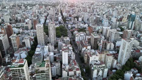 Aerial-lowering-over-Belgrano-neoghborhood-buildings-at-sunset-with-bright-sun-in-horizon,-Buenos-Aires,-Argentina