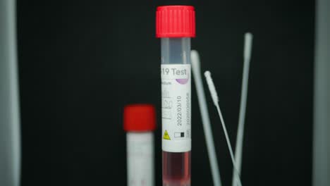 Nasopharyngeal-Swab-For-Coronavirus-In-Dublin,-Ireland---Test-Tube-With-COVID-19-Test-Sample-Spinning-With-A-6-inch-Cotton-Swabs-In-The-Background