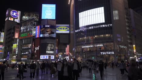 Many-people-walking-across-busy-Shibuya-Scramble-during-rainy-night---static-shot