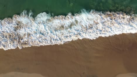 A-drone-reveals-crystal-clear-water-and-crashing-waves-on-a-beautifully-sunny-California-coast