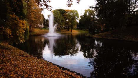 The-park-of-Kronvalda-in-Riga,-Latvia-in-beautiful-golden-autumn-season-with-huge-fountain-in-the-center-of-pond