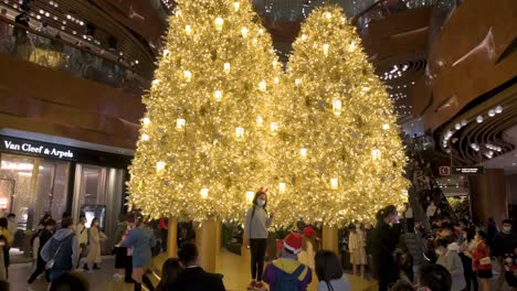 Menschen-Feiern-Die-Weihnachtsfeiertage,-Während-Sie-Vor-Einem-Goldenen-Weihnachtsbaum-In-Einem-Einkaufszentrum-In-Hongkong-Für-Fotos-Posieren
