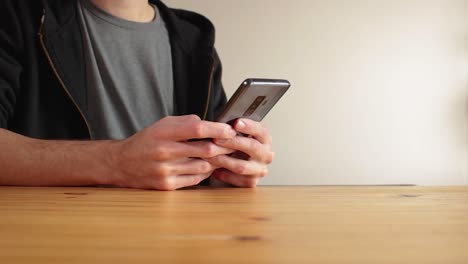 Young-man-using-dark-grey-smartphone,-texting-and-scrolling