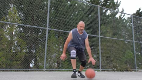 Portrait-of-a-man-practicing-basketball-moves-and-dribbling-in-front-of-the-camera,-wide-view