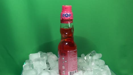 2-3-Meistverkauftes-Japanisches-Kohlensäurehaltiges-Getränk-Mit-Erdbeergeschmack-Namens-Marble-Pop-Ball,-Aktivierte-Karbonisierung-Unter-Dem-Deckel,-Um-Den-Reichen-Geschmack-Zu-Bewahren,-Rotierend-Um-360-Grad-Im-Eishaufen-Vor-Dem-Green-Screen