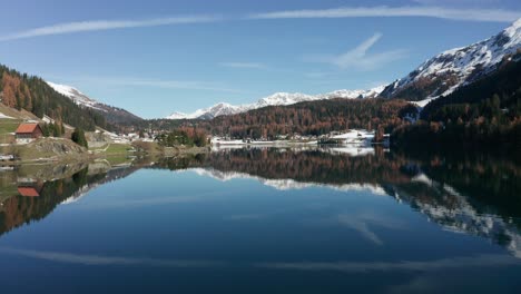 Vuelo-Hacia-Adelante-Y-Hacia-Arriba-Sobre-El-Lago-Davos,-Suiza,-Con-Magníficos-Reflejos-En-El-Agua