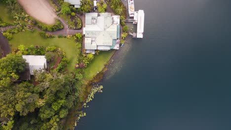 Moving-drone-video-looking-down-on-a-lush-park-area-next-to-a-volcanic-crater-lake-with-boats-docked-next-to-pontoon