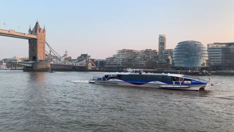 A-view-of-the-Thames-River-and-a-very-fast-ferry-traveling-down-full-of-tourists-in-front-of-Tower-Bridge