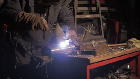 Man-shielded-metal-arc-welding-stainless-steel-pipe-in-workshop