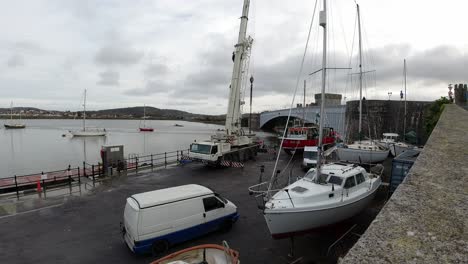 Hydraulic-crane-vehicle-lifting-fishing-boat-vessel-into-Conwy-marina-water-timelapse