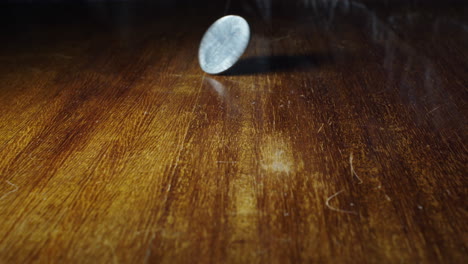 Closeup-of-coin-flipping-of-wooden-table,-10-cent-Italian-lira,-static,-slow