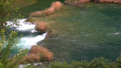 Large-volumes-of-water-flowing-from-one-pond-down-to-another-through-grass-in-Krka-National-Park-in-Croatia-at-¼-speed