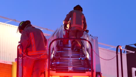 Fire-fighter-walking-up-fire-escape-stairs-of-fire-engine-with-fire-extinguisher-in-hand