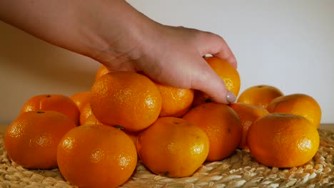 The-beautiful-female-hand-is-putting-an-orange-on-the-pile-of-oranges