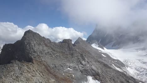 Toma-Aérea-En-Los-Alpes-Suizos-Descubriendo-Una-Cordillera-Salvaje-En-Las-Nubes