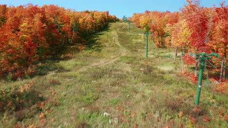 Aerial-flyover-view-ski-slope-mountain-bike-trail-in-the-fall-revealing-forested-valley
