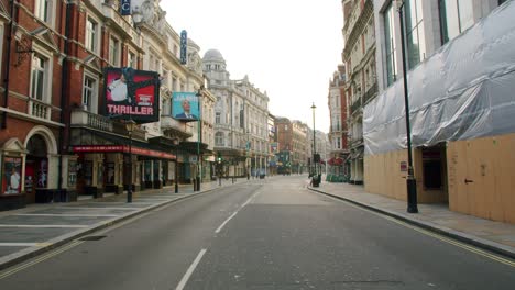 Lockdown-in-London,-closed-theatres-along-deserted-Shaftesbury-Avenue,-West-End-in-beautiful-morning-sun-light,-during-the-Coronavirus-pandemic-2020