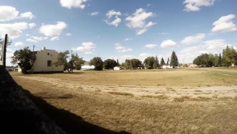 TIME-LAPSE---Sitting-on-a-wooden-fence-looking-at-a-empty-field-with-cut-grass-as-the-clouds-float-by-on-a-sunny-day