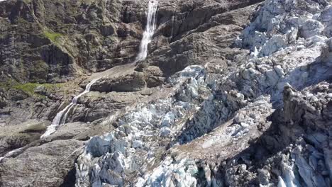 Scenic-aerial-approach-view-of-a-glacier-and-a-big-waterfall-in-the-Swiss-alps-in-summer