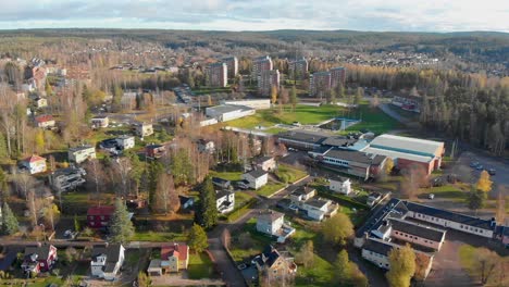 Drone-footage-flying-over-a-residential-area-and-a-school-in-a-small-town-with-a-large-swimming-pool-and-more-houses-in-the-background