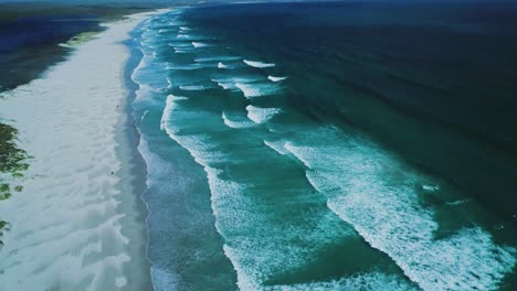 Aerial-beach-tilt-up-with-stretch-of-sand-dividing-lagoon-and-ocean-in-Hermanus,-South-Africa