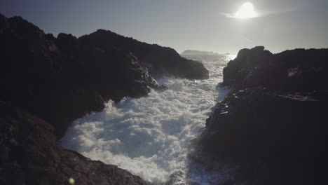 Medium-tilt-up-shot-of-splashing-ocean-wave-on-rocks-at-sunny-day-in-Ucluelet,-Vancouver-Island,-Canada
