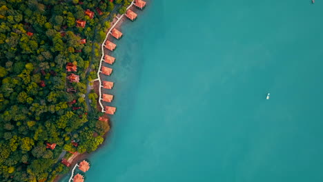 Aerial-shot-of-overwater-bungalows-along-the-rainforest-coastline,-Langkawi,-Malaysia