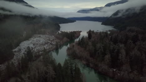Cloudy-Aerial-tilting-shot-of-winter-valley-with-river-and-mountains-on-Vancouver-island,-Canada