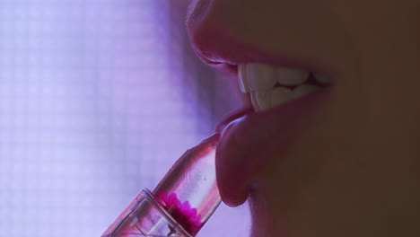 Lipgloss-is-applied-to-her-lips-while-LED-motion-lights-glow-in-the-background