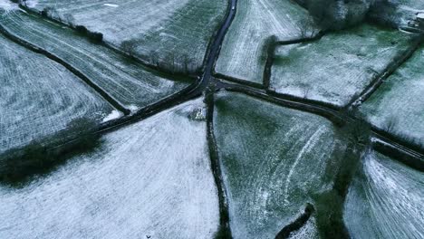 Drone-shot-of-a-car-driving-past-a-country-junction-in-a-wintry-snowy-cold-scene