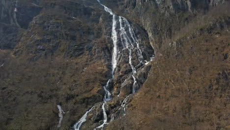 Nach-Oben-Geneigte-Luftaufnahme-Eines-Unglaublichen-Wasserfalls,-Der-In-Norwegen-Einen-Berg-Hinabstürzt,-Während-Der-Schnee-Schmilzt
