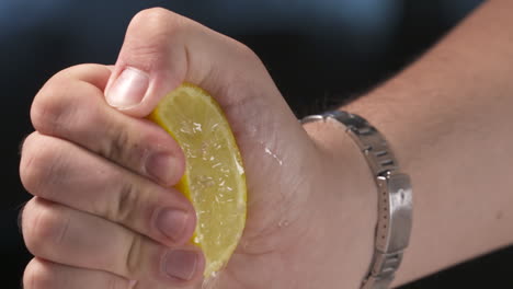 Eine-Männliche-Hand-Mit-Armbanduhr-Drückt-Eine-Frische,-Saftige-Zitrone-Aus