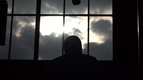 Silhouette-Eines-Geschäftsmannes,-Der-Vor-Großen-Fensterscheiben-Mit-Wolken-Und-Sonne-Die-Rolltreppe-Hinaufgeht