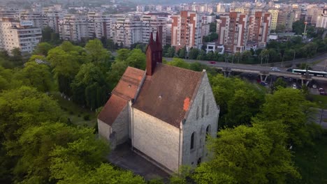 Round-View-Of-Beautiful-Church-between-trees-forest-And-View-of-monument-Town-Cluj,-Romania,-Transylvania