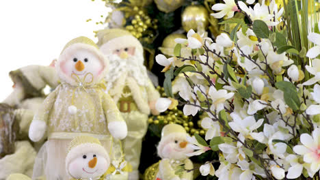Cute-snowmen-family-dolls-and-Santa-Clauss-near-Christmas-tree-and-flowers