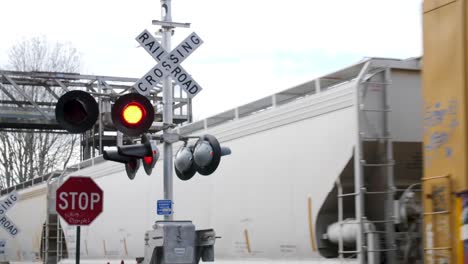 Active-railroad-crossing-sign-with-train-passing-in-the-background