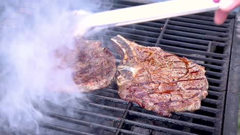 Turning-steaks-on-a-hot-charcoal-barbecue-with-some-open-flames-in-a-slow-zoom-in-motion