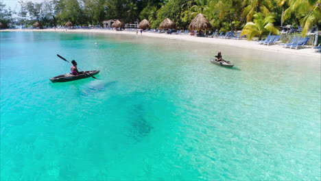 AERIAL:-Girls-kayaking-on-caribbean-beach-resort