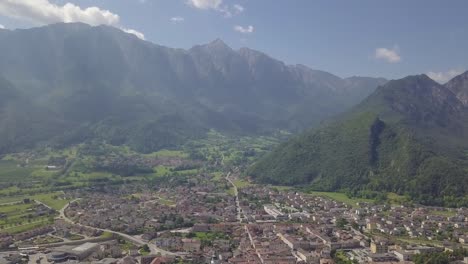 Aerial-panoramic-view-of-Borgo-Valsugana-in-Trentino-Italy-with-views-of-the-city-and-mountains,-camera-tilting-up