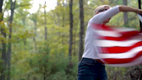 Pretty-blonde-woman-throws-the-American-flag-over-her-head-and-in-front-of-her-and-then-back-in-a-wave