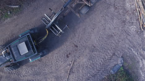 Top-down-aerial-view-of-a-tractor-and-logging-trailer-driving-through-the-frame