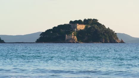 Slow-zoom-on-"Fort-de-Brégançon"-castle,-holiday-residence-of-French-presidents-at-sunset,-waves-in-the-foreground